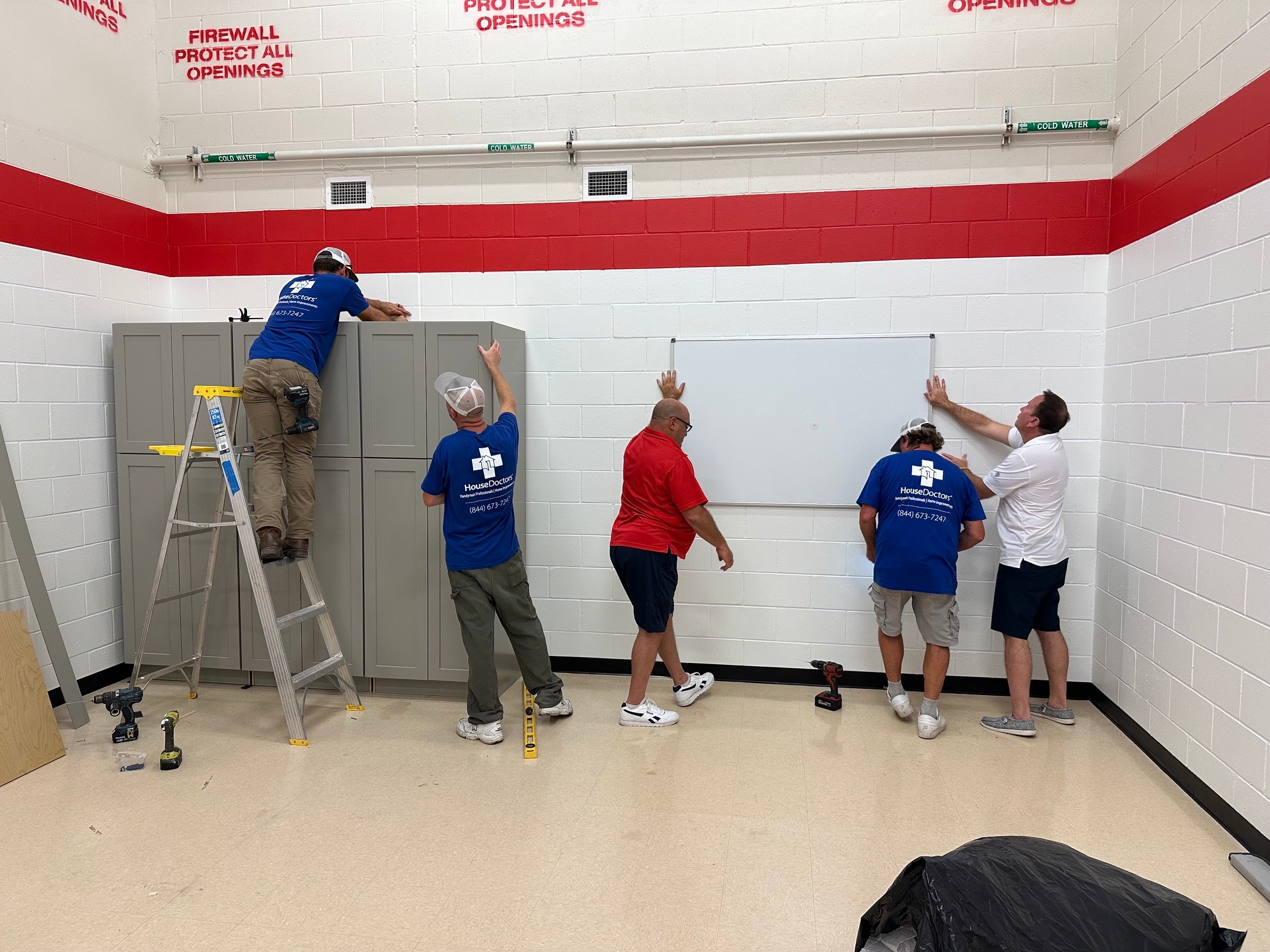 a group of people hanging a dry erase board on the wall